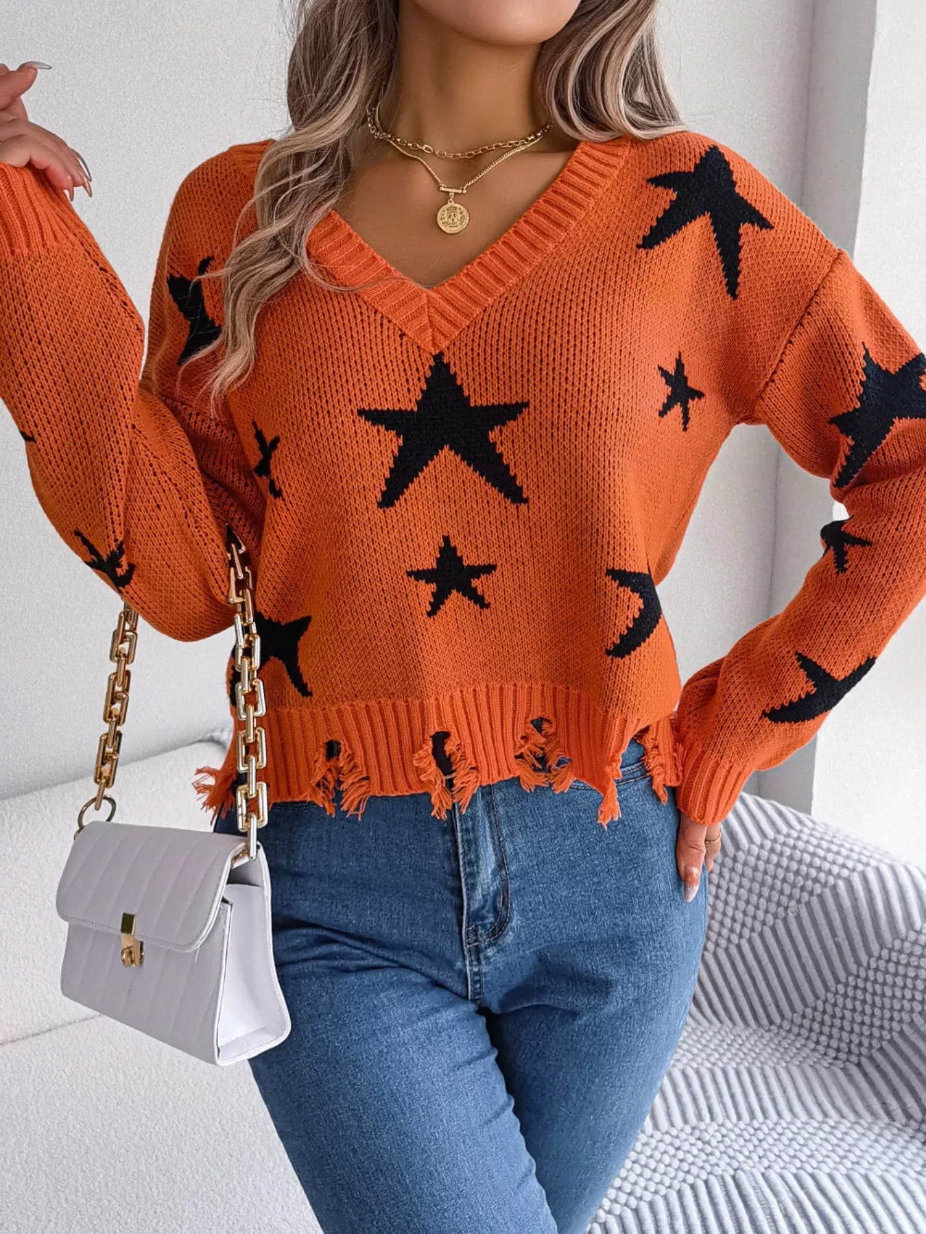 Woman in star pattern distressed sweater by fall leaves