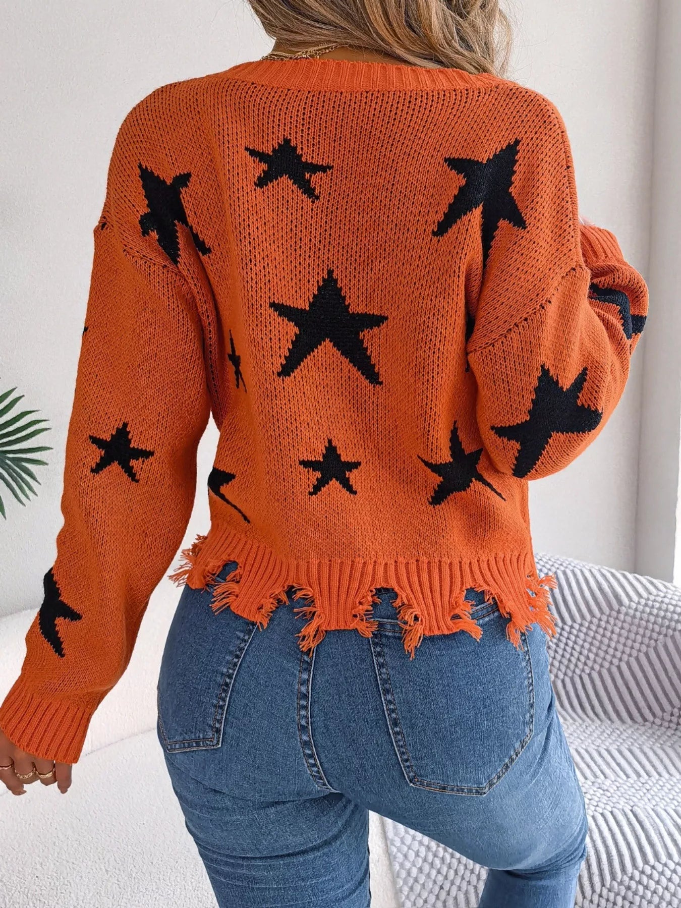 Woman in star pattern distressed sweater by fall leaves