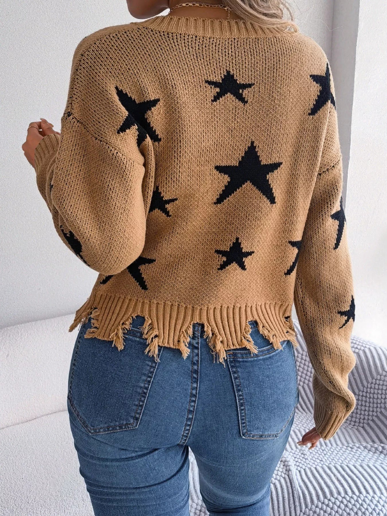 Woman in star pattern distressed sweater by fall leaves