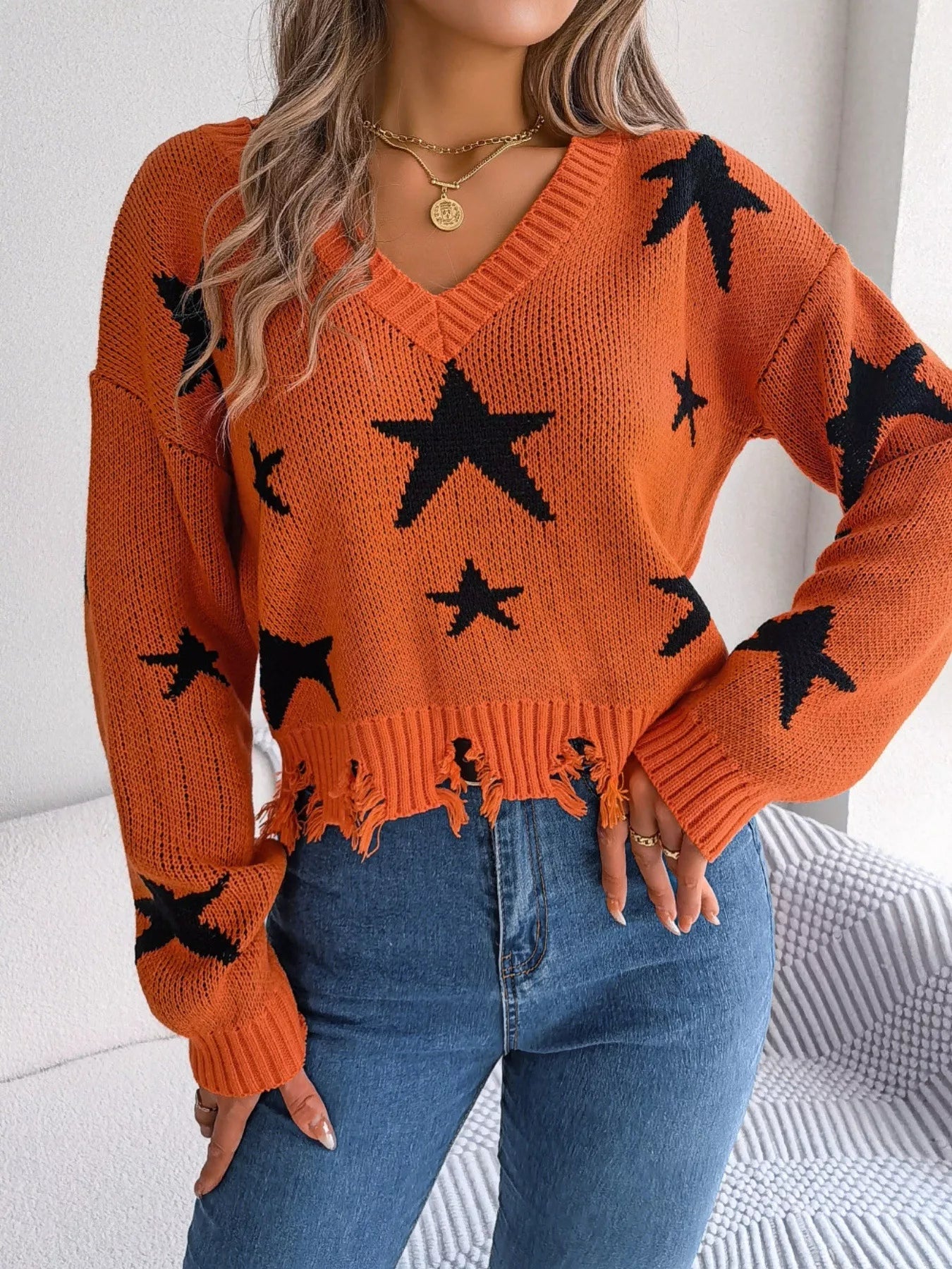 Woman in star pattern distressed sweater by fall leaves