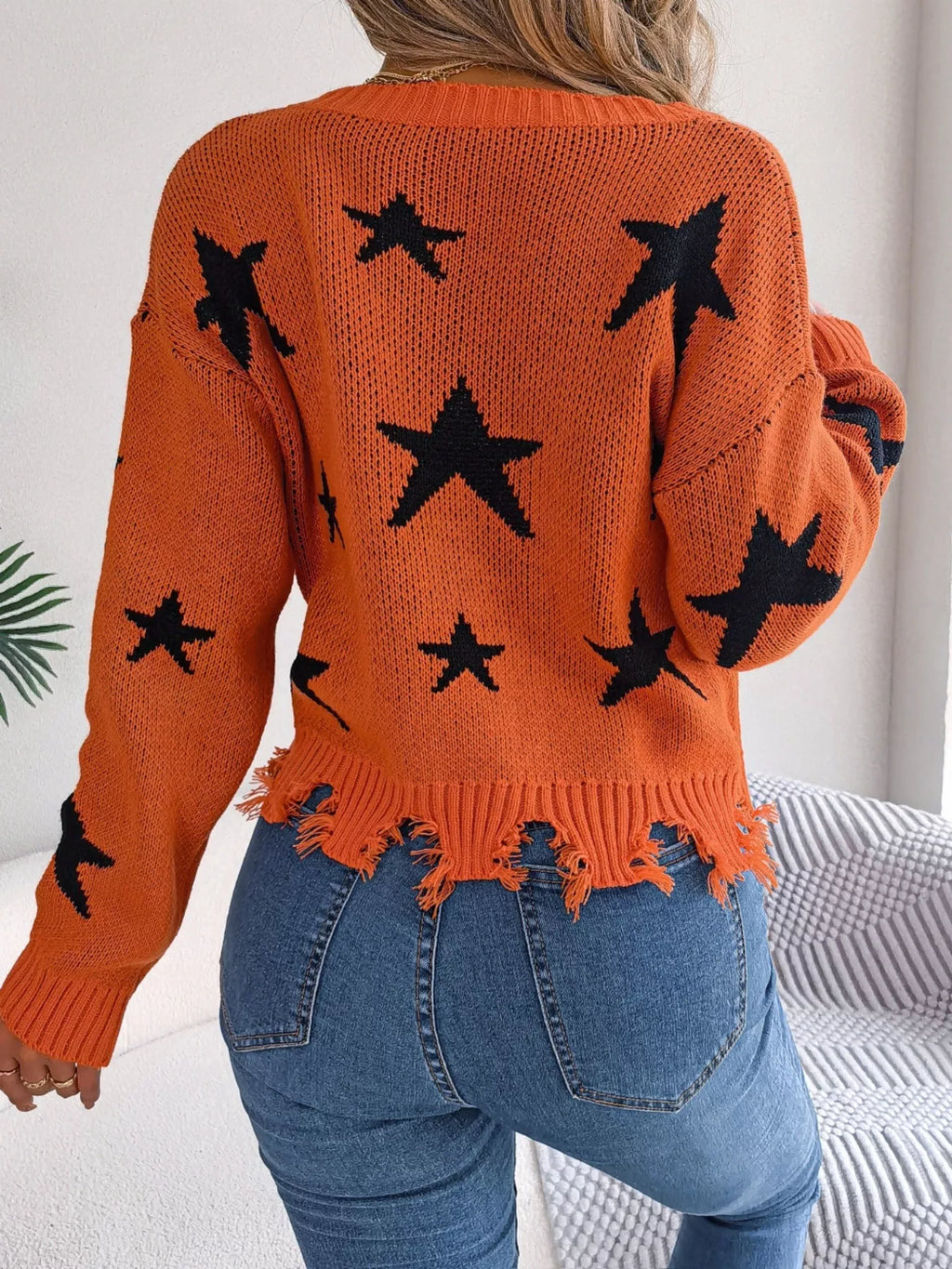 Woman in star pattern distressed sweater by fall leaves